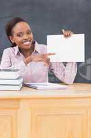 Black teacher holding a blank paper while sitting at desk