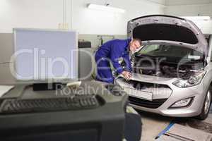 Smiling mechanic examining a car engine