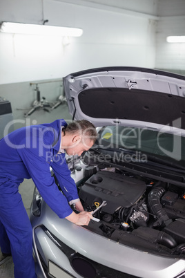 Mechanic leaning on a car while holding a spanner