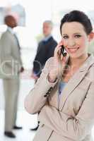 Smiling businesswoman talking on the cell phone while crossing h
