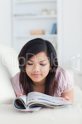 Woman holding a magazine while resting on a sofa