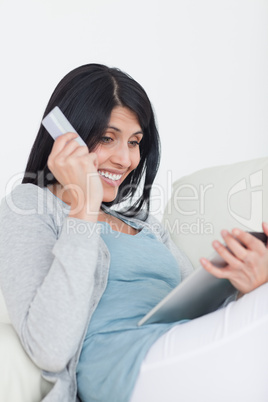 Smiling woman holding a credit card and a tablet