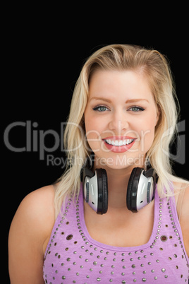 Cheerful blonde woman standing with headphones around her neck