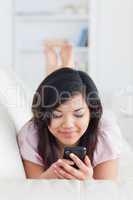 Woman lays on a couch while holding a phone
