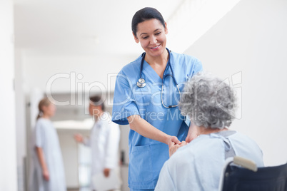 Nurse standing next to a patient while holding her hands