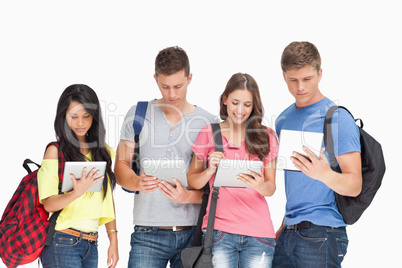 Students with backpacks looking at their tablets