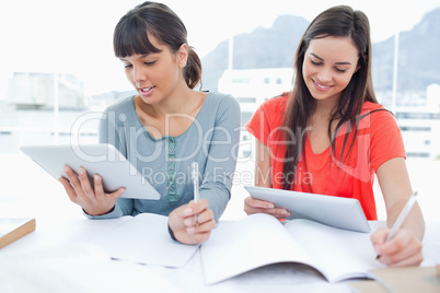 Two girls both using tablet pc's to do their homework