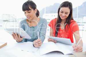 Two girls both using tablet pc's to do their homework