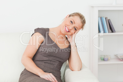 Woman sitting on a sofa while holding her head with her hand