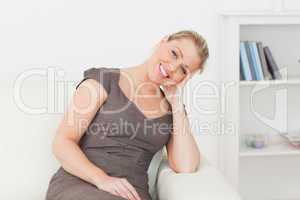 Woman sitting on a sofa while holding her head with her hand
