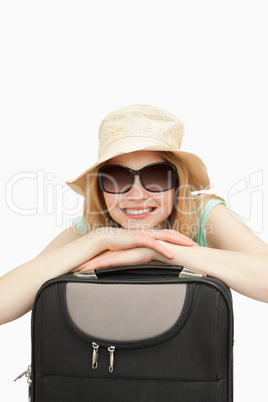 Close up of a smiling woman leaning on a suitcase