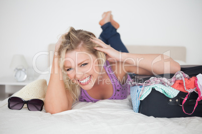Woman having a giggling next to her full suitcase