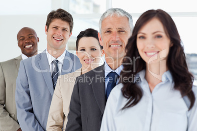 Young smiling executive standing in a well-lit room among his co