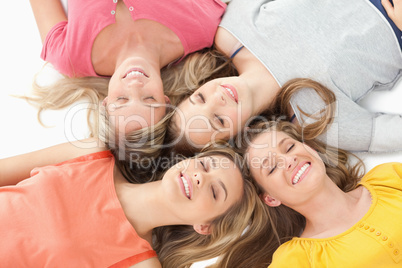 Four girls with their eyes closed and smiling while on the groun