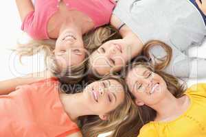 Four girls with their eyes closed and smiling while on the groun