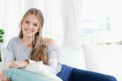 Smiling girl lying on the couch looking at the camera