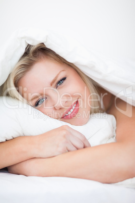 Young blue eyed woman embracing a pillow