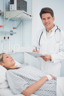 Doctor writing on his clipboard next to his patient