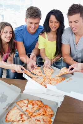 A group grabbing themselves a slice of the pizza