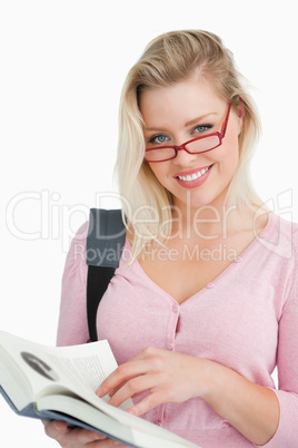 Happy young woman wearing glasses while holding a novel