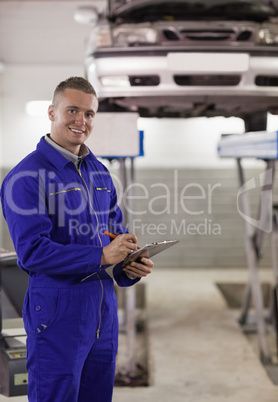 Smiling mechanic writing on a clipboard Smiling mechanic writing on a clipboard