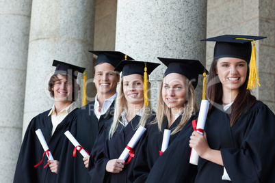 Smiling graduates posing in single line