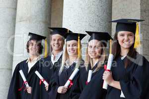 Smiling graduates posing in single line