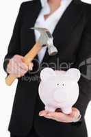 Businesswoman holding a piggy-bank and a hammer