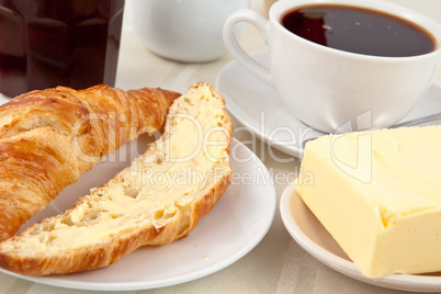 Breakfast with a croissant spread with butter