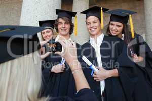 Close-up of a blonde graduate taking a picture of her friend