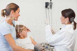 Doctor preparing a syringe next to a child and his mother