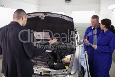 Client looking at a car next to mechanics