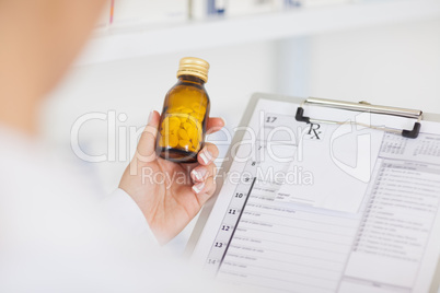 Pharmacist holding a drug bottle and a clipboard