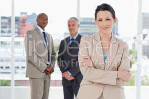 Young secretary crossing her arms in front of two business peopl