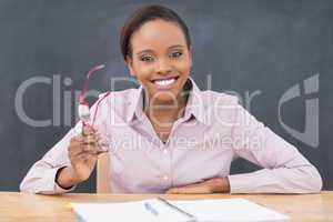 Teacher sitting at desk while holding glasses