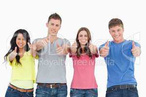 Four people standing beside each other give thumbs up