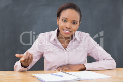 Teacher sitting at desk next to a notebook