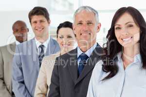 Four smiling employees standing upright around their director
