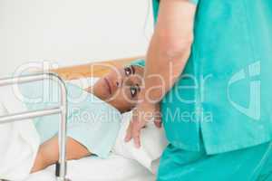 Female patient lying on a bed while looking a doctor