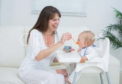 Mother sitting in a sofa while feeding a baby