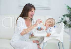 Mother sitting in a sofa while feeding a baby