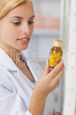 Blonde pharmacist looking at a drug bottle
