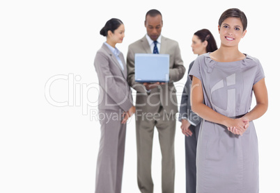 Woman welcoming and co-workers with a laptop in the background