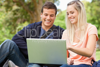 Young people sitting while using a laptop