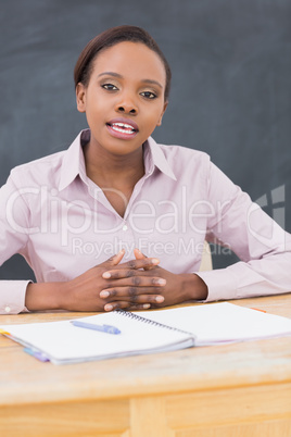 Teacher sitting at desk while speaking