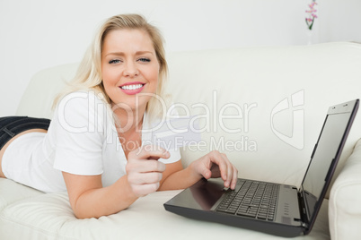 Casual woman lying with a credit card and a laptop