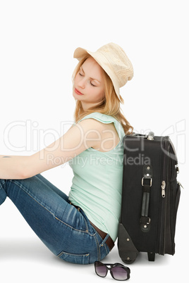 Blonde-haired woman sitting against a suitcase