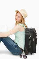 Blonde-haired woman sitting against a suitcase