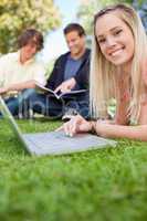 Close-up of a girl using a laptop while lying in a park