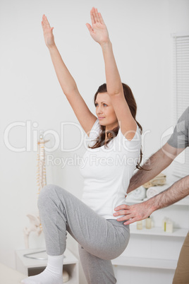 Woman doing exercise while a man is putting his hands on her hip